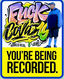 a man in a blue jacket is standing in front of graffiti that says marco real you 're being recorded