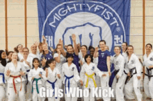 a group of girls in karate uniforms are posing for a picture in front of a banner that says `` girls who kick '' .