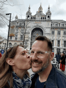 a woman kisses a man on the cheek in front of a building with a sign that says ' bakery ' on it