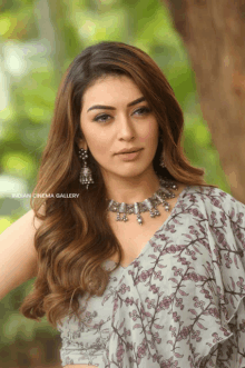 a woman wearing a floral dress and a necklace with the words indian cinema gallery on the bottom right