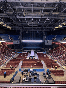 a large empty stadium with rows of red seats and a large stage