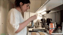 a woman in a white shirt is preparing food in a kitchen with a box of anilboray on the counter