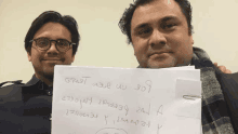 two men are holding up a piece of paper that says gracias on it