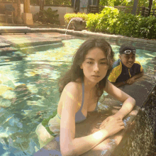 a woman in a bikini is leaning against the edge of a swimming pool