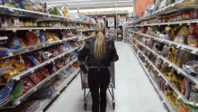 a woman pushing a shopping cart in a grocery store aisle with a sign that says thanks you for shopping with us