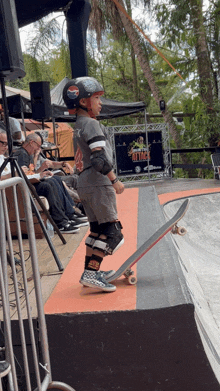 a young boy on a skateboard in front of a sign that says ' blitz ' on it