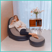 a woman sits on an inflatable chair drinking coffee