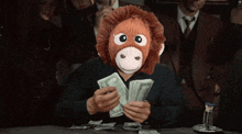 a man wearing a stuffed monkey mask holds a pile of money