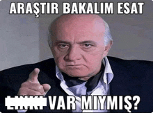 a man in a suit and tie is pointing at the camera with the words " arastir bakalim esat " written below him