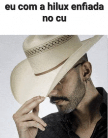 a man wearing a cowboy hat with the words eu com a hilux enfiada no cu