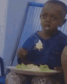 a young boy is sitting at a table eating a salad with a fork .