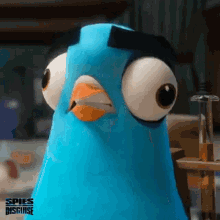 a blue cartoon pigeon with big eyes is standing next to a table .