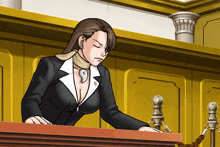 a woman in a suit stands at a podium in a courtroom with her eyes closed