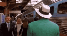 a man in a green jacket and white hat is standing in front of a sign that says washington dc