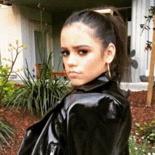 a woman is wearing a black leather jacket and a ponytail .