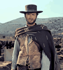 a man with a beard wearing a hat and a vest with the letter t on it