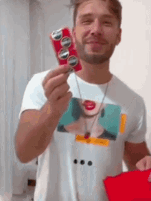 a man wearing a white shirt with a picture of a woman on it is holding a can of coke