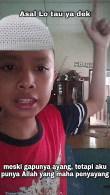 a young boy wearing a white hat and a red shirt is making a gesture with his hand .