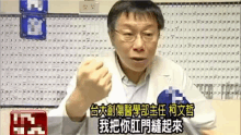 a man in a white coat and glasses is talking in a room with chinese writing on the wall .