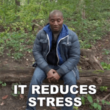 a man in a blue jacket sits on a log in the woods with the words it reduces stress below him