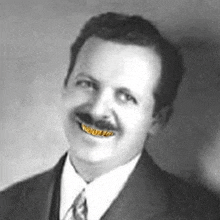 a black and white photo of a man in a suit and tie with a gold grill on his teeth .