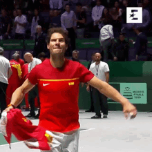 a man in a red shirt is holding a red flag in front of a sign that says madrid open