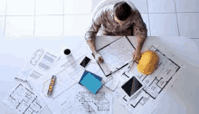 a man is sitting at a table with a hard hat and drawings on it .