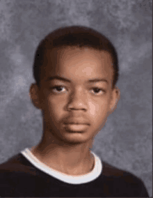 a young boy is posing for a picture in front of a grey background