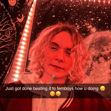 a man with long blonde hair is holding a straw in his mouth in front of a galaxy tapestry