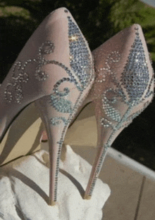 a pair of high heels with rhinestones on them are on a rock .