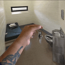 a person with a tattoo on their arm holds keys in a cell