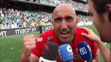 a man wearing a red shirt with the word macron on the front