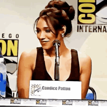 a woman sitting in front of a microphone with a sign that says cantice patton