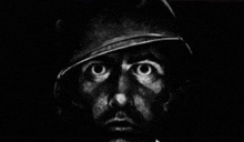 a black and white photo of a soldier 's face with a helmet on .