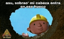 bob the builder is sticking his head out of a hole in the dirt .