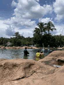 a group of people are swimming in a pool with a fountain and palm trees in the background