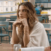 a woman is sitting at a desk in a classroom with a cup of coffee and a book on it .