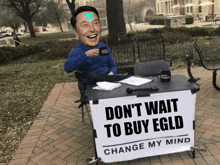 elon musk is sitting at a desk with a sign that says " don t wait to buy egld "