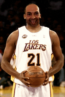 a man wearing a los lakers jersey holds a spalding basketball