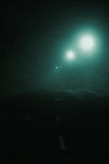 two street lights are lit up in the foggy night