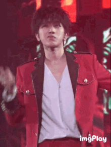 a young man in a red jacket is dancing on a stage .