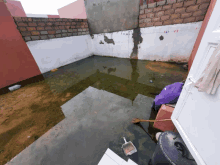 a dirty corner of a building with a bucket and a broom in the water