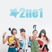 a group of people standing next to each other in front of a white wall with the word 2ne1 on it .