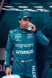 a man in a racing suit with the word cognizant on it drinks from a cup