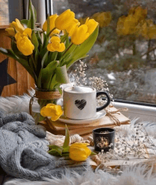 a cup of coffee sits on a window sill next to a vase of yellow flowers