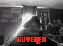 a black and white photo of a man with the words guvened in red