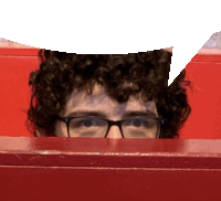 a man with curly hair and glasses peeking over a red wall with a speech bubble above his head