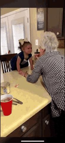 a little girl is sitting at a table with an older woman in front of a sign that says hugs