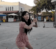 a woman in a pink dress stands on a sidewalk in front of a building that says ' el dia '