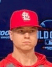 a young man wearing a red baseball cap is standing in front of a blue wall .